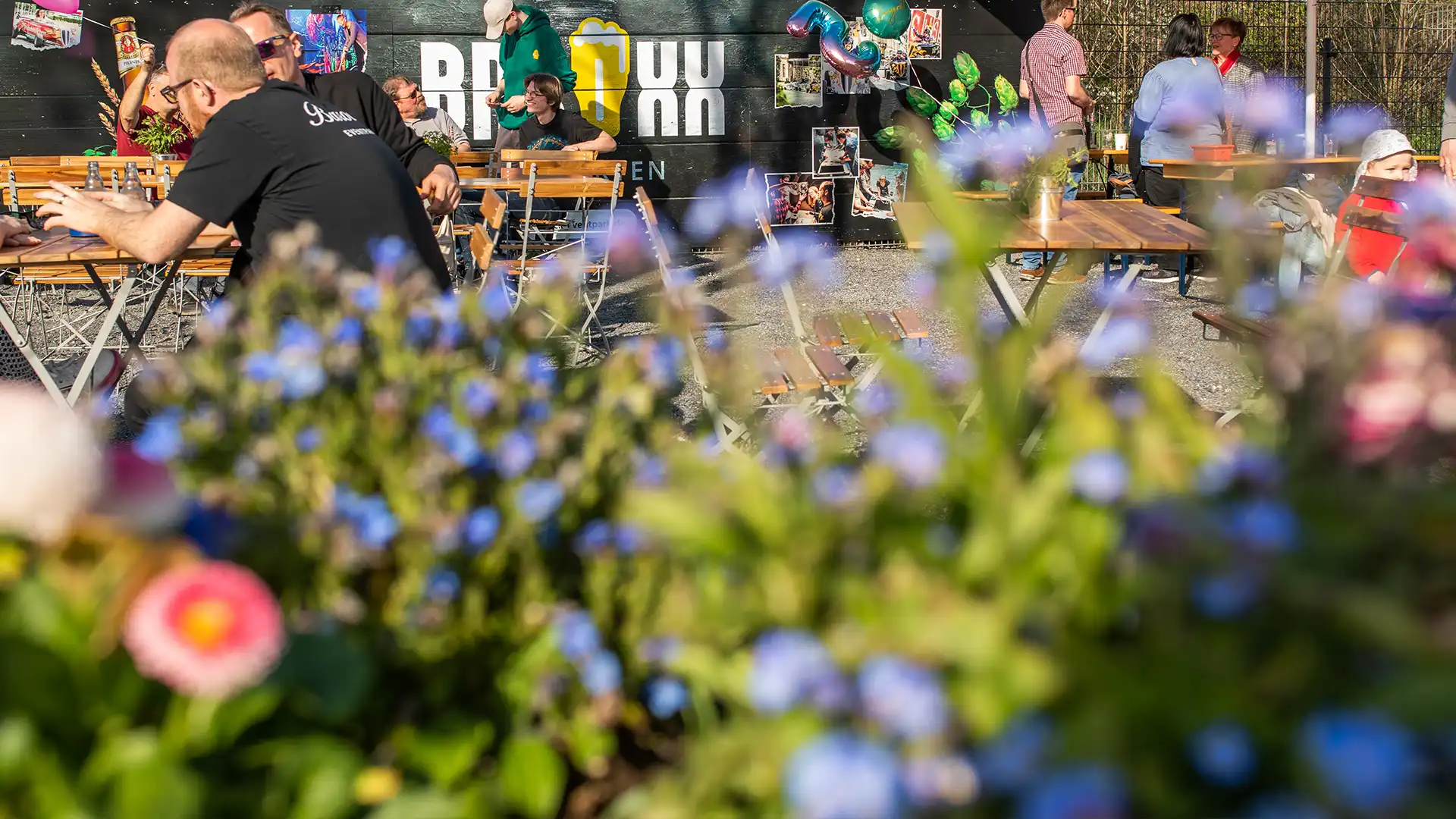 BAROXX® Biergarten Gäste im BAROXX® Biergarten hinter bunten Blumen