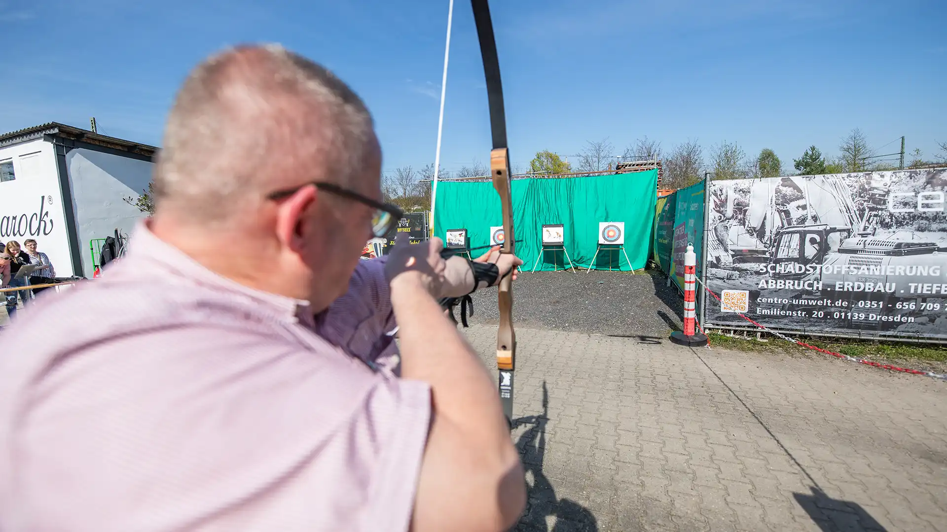 Mann zielt beim ARROXX® Bogensport mit Curvebogen und Pfeilen auf Zielscheibe - Barock Eventpark Dresden